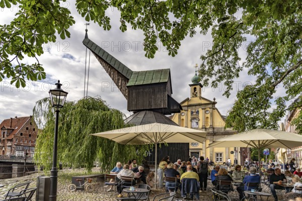 Beer garden at the Old Harbour with crane and hotel department store in the Hanseatic city of Lüneburg, Lower Saxony, Germany