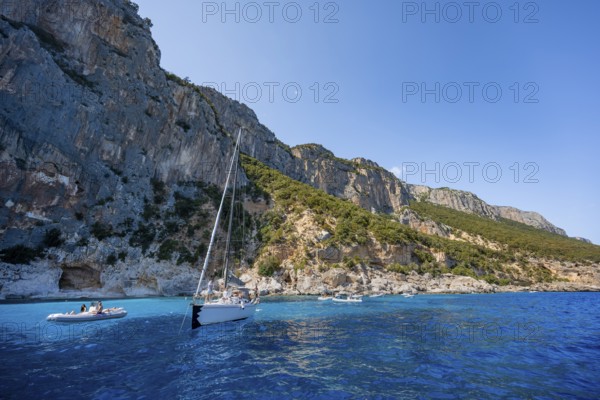 Picturesque rocky coast, sailboat off cliffs and blue sea at Piscine di Venere, Golfo di Orosei, Baunei, Sardinia, Italy