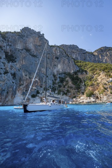 Picturesque rocky coast, sailboat off cliffs and blue sea at Piscine di Venere, Golfo di Orosei, Baunei, Sardinia, Italy