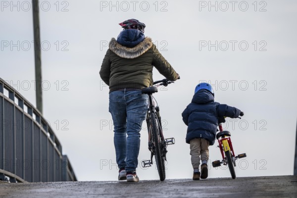 Father and son push their bikes up a steep bicycle bridge together