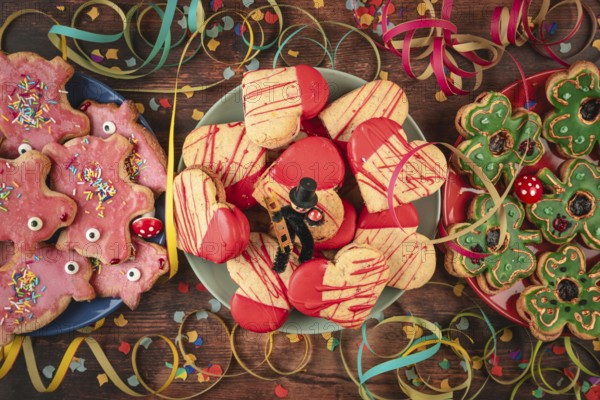 Various colorful cookies on wooden table with confetti, streamers and lucky charms