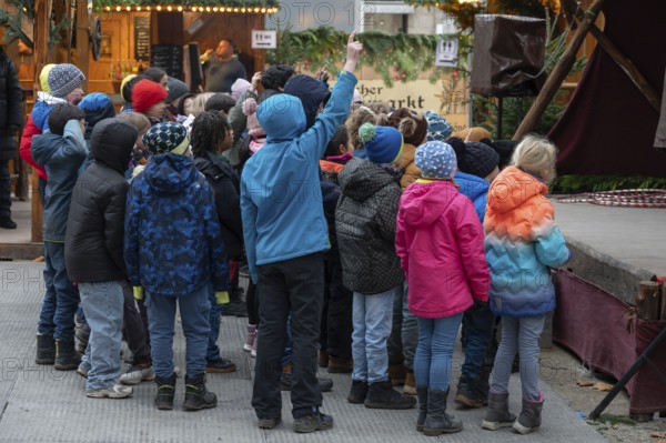 A group of children watches an acrobat on stage, Historischer Christmas market am Neustädter church square, Erlangen, Middle Franconia, Bavaria, Germany
