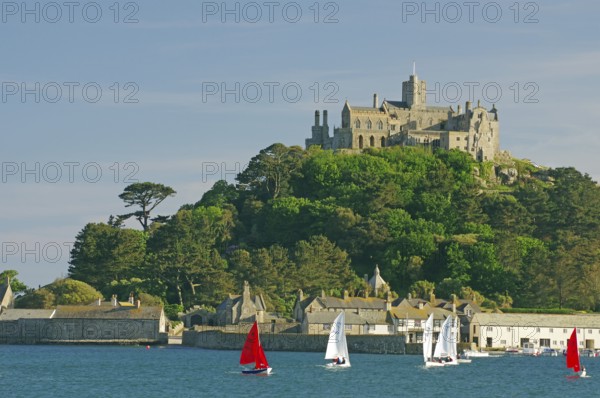 A castle overlooks the sea surrounded by sailing boats and green nature, Penzance, Saint Michael's Mount, Cornwall, Great Britain
