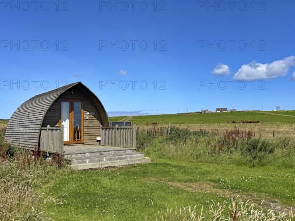 Small wooden house on a green field under clear blue sky on a sunny day, Pod, holiday accommodation, Orkney Islands, Scotland, United Kingdom