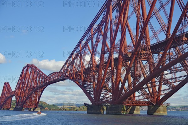 An imposing red steel bridge spanning a river under a blue sky, railway bridge, Firth of Forth, Edinburgh, Scotland, Great Britain