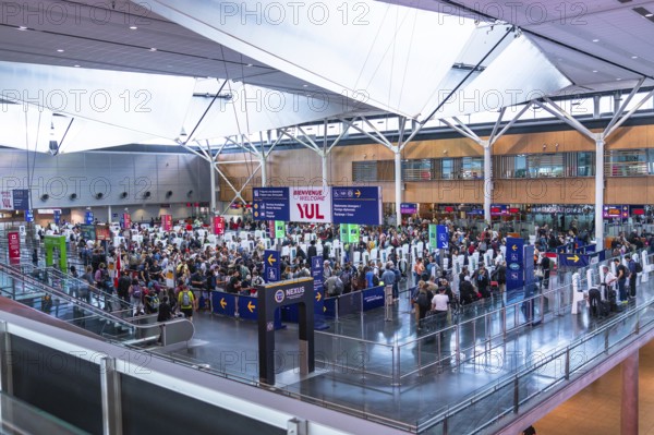 Crowds of international passengers navigating immigration control at pierre elliott trudeau international airport in montreal, canada, create a bustling scene of modern architecture and signage