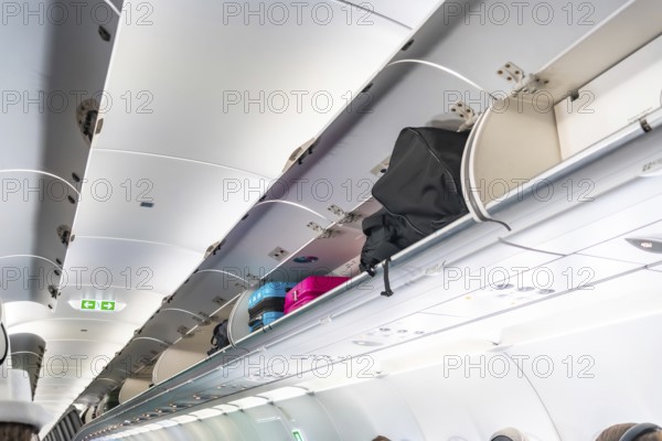 Carry on luggage and bags are neatly arranged inside the overhead compartments of an airplane cabin, ensuring passenger comfort and convenience during a flight