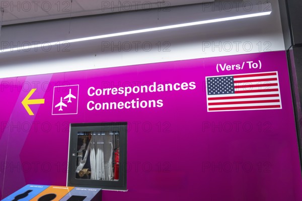 Bright pink airport sign with airplane icons and the flag of the united states of america, guiding passengers to connecting flights or destinations within the country