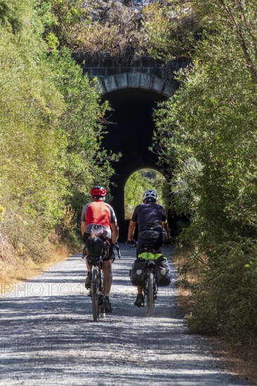 Couple riding bicycle, cycle path Via Verde de la Sierra, Puerto Serrano to Olvera, old railroad track, cycle path leading through a tunnel, near village Coripe, Andalusia, Spain