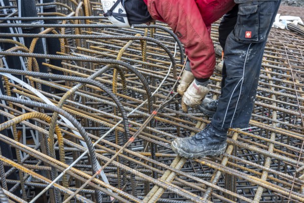 Assembly of reinforcing steel for the reinforced concrete foundation of a wind turbine, a mesh of rebar and reinforcing steel mesh, connecting the steel elements with binding wire, twisting with tongs, over 100 tons of reinforcing steel were used, the wind turbine will have a hub height of 160 meters, part of a new wind farm in Sauerland, near Balve, North Rhine-Westphalia, Germany