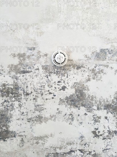 Round ceiling sprinkler nozzle in minimalistic concrete ceiling with chipped paint and abstract structure, Wuppertal, Germany