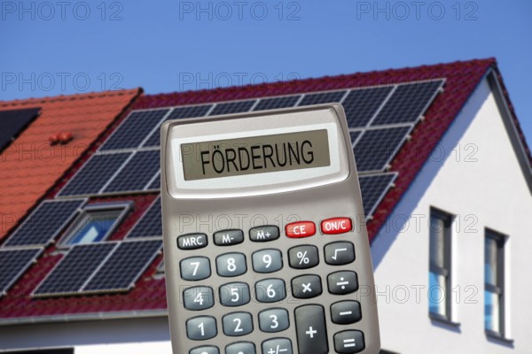 (photo montage) Pocket calculator with the inscription PROMOTION in front of a solar roof