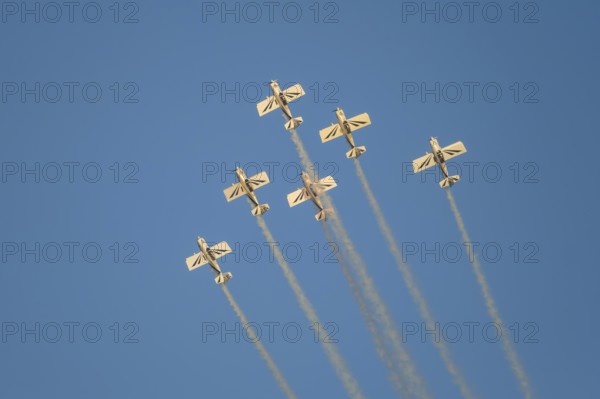 Stunt aerobatic planes performing stunts in blue sky with smoke trail. Concept of teamwork, collaboration, coordination, trust, precision, difficulty, challenge, speed, synergy