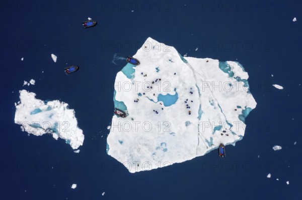 Aerial view over ecotourists from Iceland Pro Cruises walking on ice floe drifting in the Arctic Ocean in summer at Svalbard / Spitsbergen, Norway