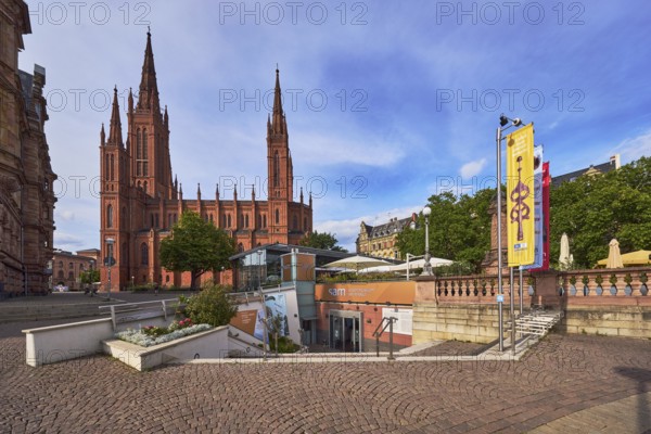 Sam - Stadtmuseum am Markt, entrance, staircase, flower bed, advertising flag on flagpoles, sandstone wall, Protestant market church community Wiesbaden, church market church, neo-Gothic style, architect Carl Boos, square made of paving stones, outdoor area of a restaurant, historic building, trees, blue sky, cumulus clouds, market square, Wiesbaden, state capital, district-free city, Hesse, Germany