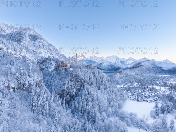 Neuschwanstein Castle is nestled in a quiet, snow-covered alpine landscape at dawn, Schwangau near Füssen, Ostallgäu, Allgäu, Bavaria, Germany