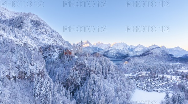 The picturesque Neuschwanstein Castle in winter surrounded by snow-capped mountains and forests at dawn, Schwangau near Füssen, Ostallgäu, Allgäu, Bavaria, Germany