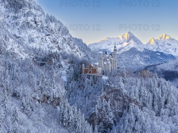 The magnificent Neuschwanstein Castle, surrounded by mountains and glowing snow in the morning light, atmospheric, Schwangau near Füssen, Ostallgäu, Allgäu, Bavaria, Germany
