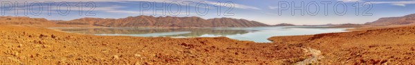 Wide desert landscape with a lake and mountains under clear sky, reservoir, Al-Hassan Addakhil Barrage in Morocco