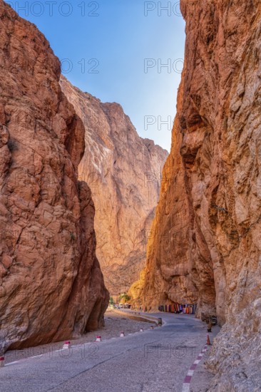 Narrow road leads through dramatic red rock formations at dusk, Todra Gorge in Morocco