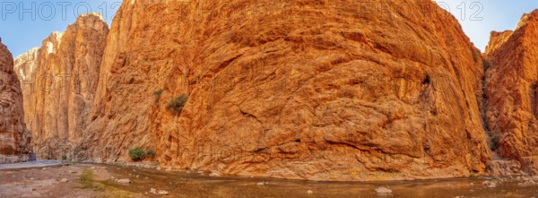 Panoramic view of gigantic red rock face under clear sky, Todra Gorge in Morocco