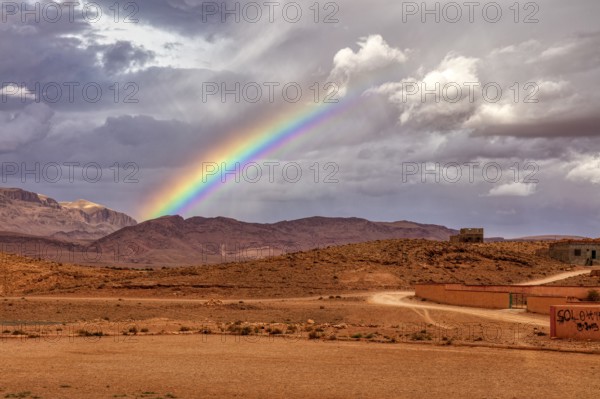 Colourful rainbow over a rural desert landscape with mountains in the background, Tinghir in Morocco