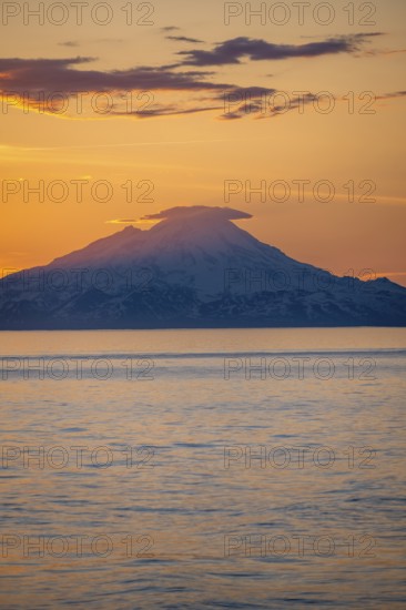 View of Cook Inlet on white mountain peaks of Mount Redoubt at sunset, picturesque golden light of the midnight sun, mountains of the Aleutian Range, Anchor Point, Anchor River State Recreation Area, Alaska, USA