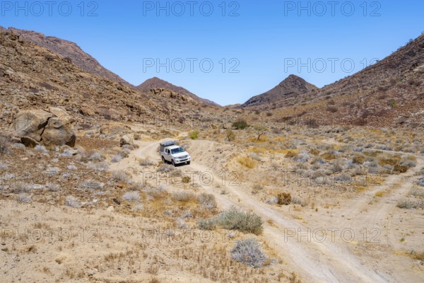 Toyota Hilux off-road vehicle on a sandy track, desert landscape with Brandberg, Erongo, Damaraland, Namibia