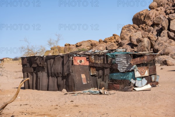 Simple poor huts made of corrugated iron and wood, desert landscape, barren landscape with hills of stacked rocks, Brandberg, Erongo, Damaraland, Namibia