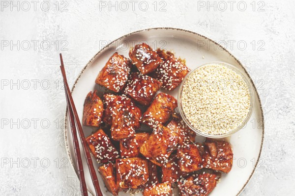 Fried pieces of salmon teriyaki with sesame seeds, top view
