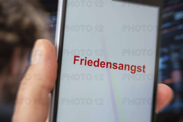 (photo montage) Smartphone with displayed text FEAR OF PEACE against the backdrop of a stock market***The term has recently been used in several articles in connection with US President Donald Trump's peace plan for Ukraine