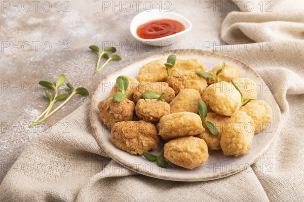 Fried crispy Chicken Nuggets with ketchup, microgreen on brown concrete background and linen textile. side view, close up