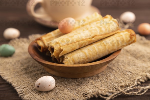 Waffles with caramel on brown wooden background and linen textile, cup of coffee, side view, selective focus