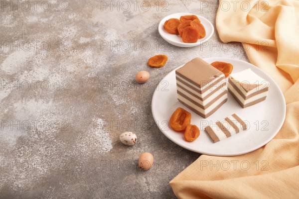 Cocoa and milk jelly with dried apricots on brown concrete background and orange textile, side view, copy space, minimalism