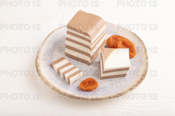 Cocoa and milk jelly with dried apricots on white wooden background, side view, close up, minimalism