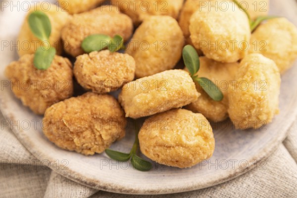 Fried crispy Chicken Nuggets with ketchup, microgreen on brown concrete background and linen textile. side view, close up, selective focus