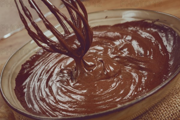 A bowl of chocolate dough, a whisk for whipping, baking, structure and consistency, homemade, top view, no people