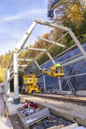 Construction work at a tunnel entrance in autumn with yellow construction equipment and visible nature in the background, Hermann Hesse Railway bat tunnel construction site, Calw, Black Forest, Germany