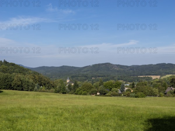 Small village with church in a gentle mountain landscape and meadows, Lusetian Mountains, Bohemia, Czech Republic