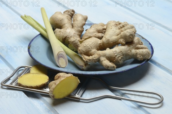 Ginger tubers and lemongrass on plate, grater with ginger pieces