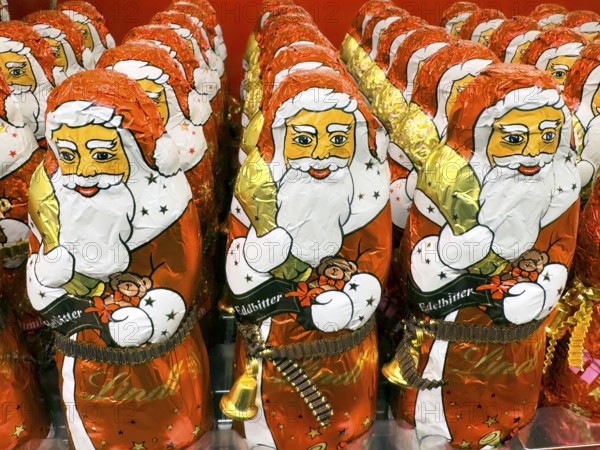 Display on the shelf of chocolate Santa Claus chocolate Santa Claus Santa Claus Santa Claus Santa Claus chocolate Santa Claus chocolate Santa Claus chocolate lice Santa Claus chocolate lice Santa Claus in color red of red staniol paper made of chocolate arranged like army of Santa Claus, Germany
