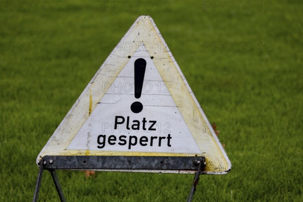 Sign with the inscription PLACE BLOCKED on a sports field (symbol image)