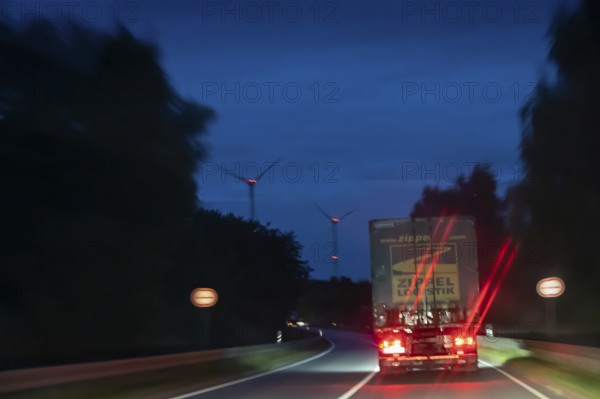 Truck on federal highway at night, wind turbine lights on the left, Schleswig-Holstein, Germany