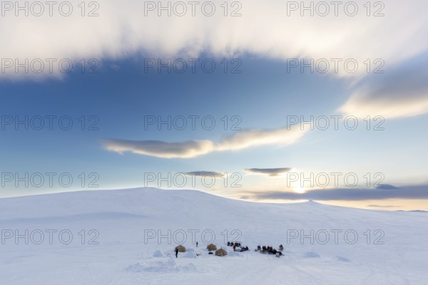 Snowmobiles, snow scooters at Arctic expedition camp with tents protected by tripwire fence against polar bears at Mohnbukta, Spitsbergen, Svalbard