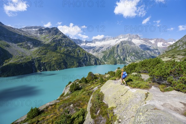 Female mountaineer in front of picturesque mountain landscape, turquoise-blue mountain lake Göscheneralpsee, Dammastock and Damma glacier, Göscheneralp, Canton of Uri, Switzerland