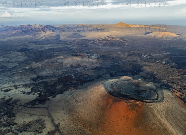 Caldera Colorada volcano, picturesque volcanic landscape with volcanic craters and lava fields in morning light, Parque Natural de Los Volcanes, aerial view, Lanzarote, Canary Islands, Spain