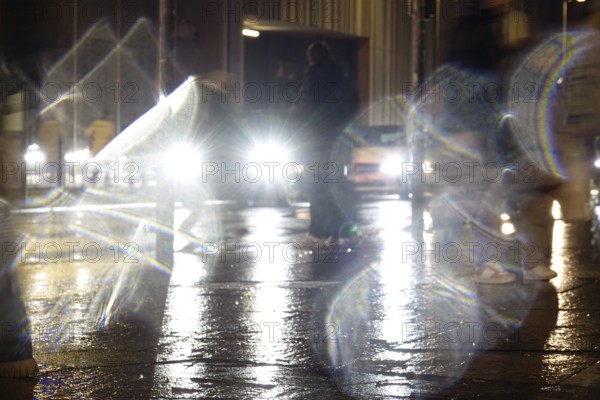 Passers-by in the evening in rainy weather in a city, November, Germany