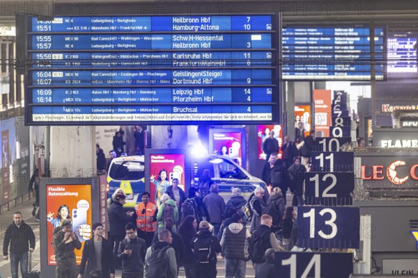 Travelers at the main train station, passengers and departure board at Stuttgart main station. Police vehicle with flashing lights. Stuttgart, Baden-Württemberg, Germany