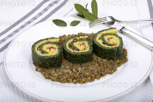 Southern German cuisine, polenta spinach roulade with alblentils served on serving platter, bay leaves, lentil vegetables, smoked meat, bacon cubes, healthy, food photography, studio, Germany