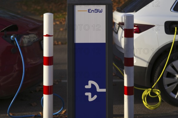 Parking lot with gas pump, EnBW charging station for electric cars, charging station, e-charging station, e-mobility, charging cable leads into two vehicles, e-car, pictogram, logo, Stuttgart, Baden-Württemberg, Germany